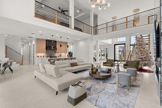 living room featuring a high ceiling, ceiling fan with notable chandelier, and sink