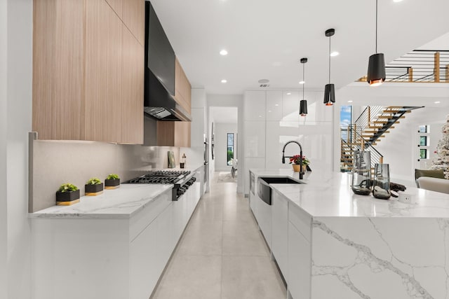 kitchen featuring white cabinetry, light stone counters, decorative light fixtures, and stainless steel gas stovetop