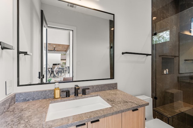 bathroom with walk in shower, vanity, and toilet