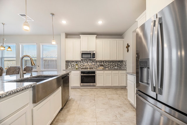 kitchen featuring light stone countertops, stainless steel appliances, and hanging light fixtures