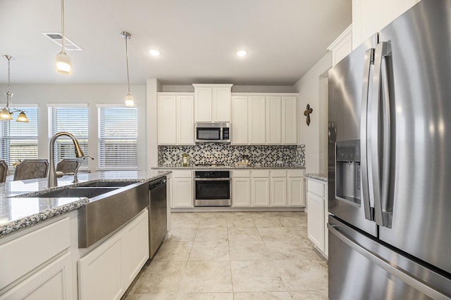 kitchen with appliances with stainless steel finishes, hanging light fixtures, and white cabinets