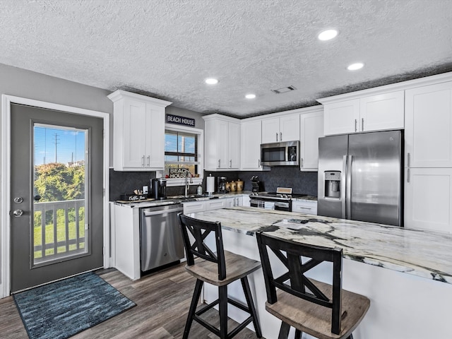 kitchen featuring dark hardwood / wood-style flooring, white cabinets, a healthy amount of sunlight, and appliances with stainless steel finishes