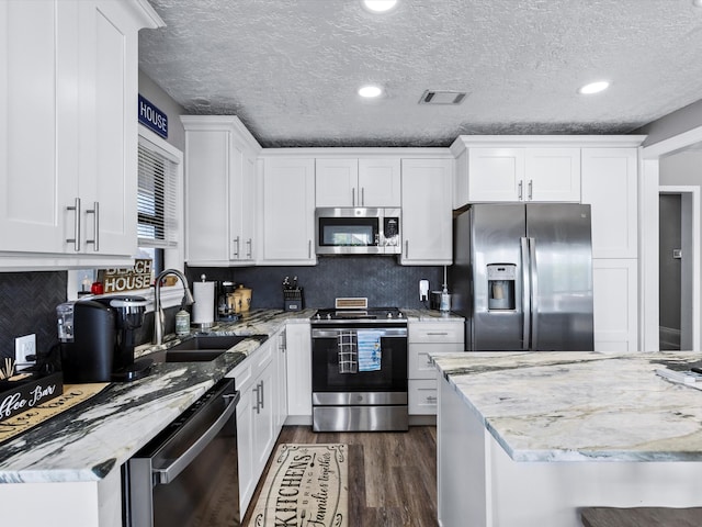 kitchen featuring light stone countertops, appliances with stainless steel finishes, white cabinetry, and sink