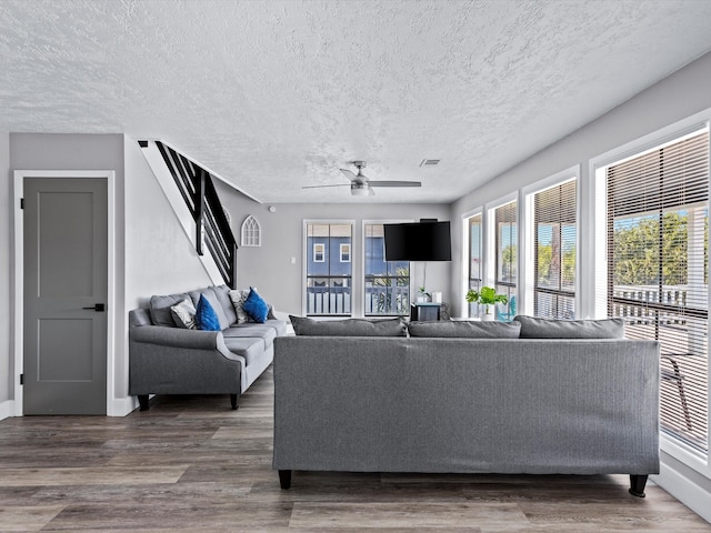 living room featuring wood-type flooring, a textured ceiling, and ceiling fan