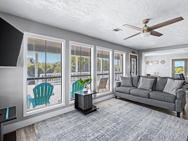 living room featuring hardwood / wood-style flooring, ceiling fan, and a textured ceiling