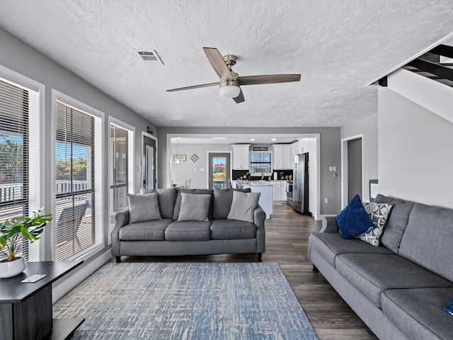 living room featuring dark hardwood / wood-style floors, ceiling fan, a textured ceiling, and a baseboard radiator