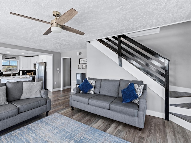 living room with ceiling fan, dark wood-type flooring, and a textured ceiling