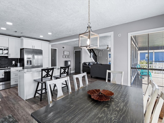 dining room with ceiling fan, dark hardwood / wood-style flooring, and a textured ceiling