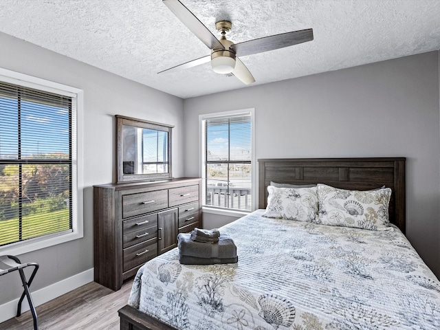 bedroom featuring ceiling fan, light wood-type flooring, and a textured ceiling