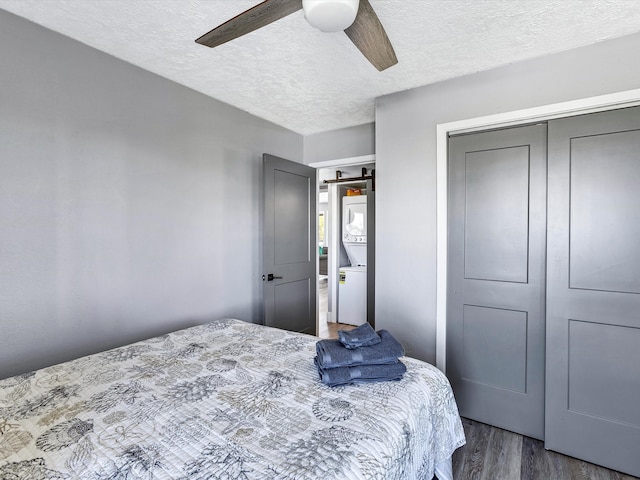 bedroom with dark hardwood / wood-style flooring, a closet, ceiling fan, and stacked washer and clothes dryer