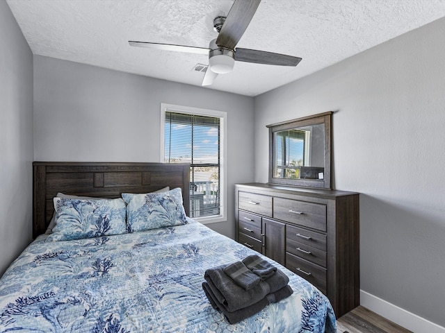 bedroom with wood-type flooring, a textured ceiling, and ceiling fan