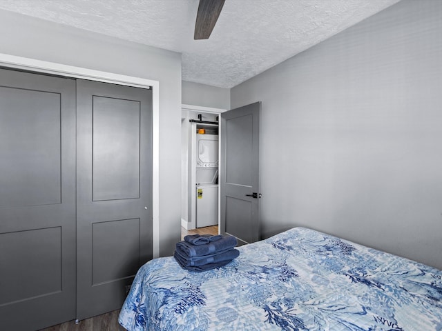 bedroom with ceiling fan, dark hardwood / wood-style floors, a textured ceiling, and a closet