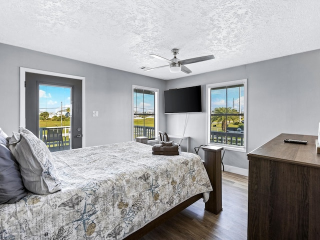 bedroom with access to exterior, a textured ceiling, dark hardwood / wood-style floors, and ceiling fan