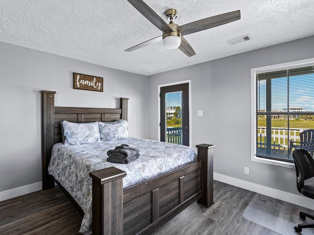 bedroom with multiple windows, ceiling fan, dark hardwood / wood-style flooring, and a textured ceiling