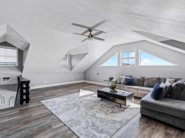 living room with a textured ceiling, ceiling fan, dark hardwood / wood-style floors, and vaulted ceiling