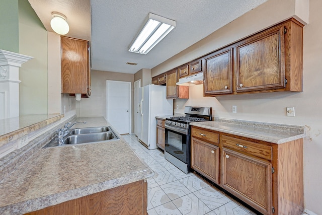 kitchen with kitchen peninsula, a textured ceiling, sink, white refrigerator with ice dispenser, and stainless steel gas stove