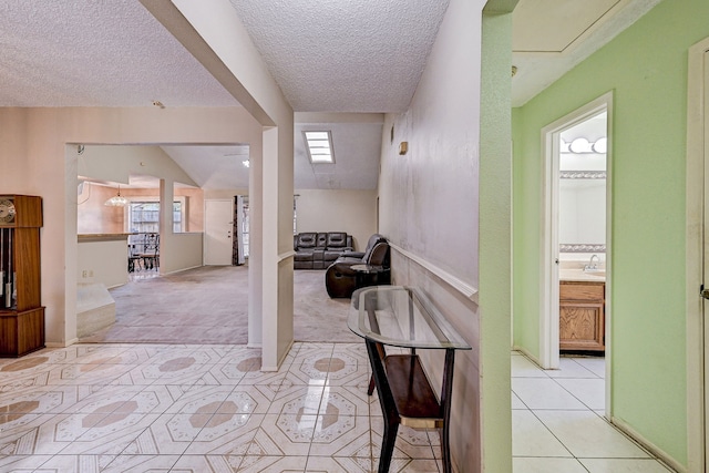 hall with light carpet, a textured ceiling, and sink