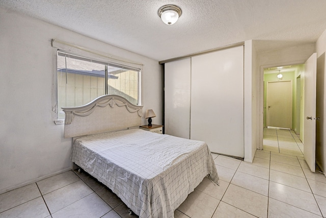 tiled bedroom with a closet and a textured ceiling