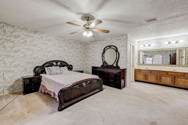 carpeted bedroom featuring ensuite bathroom, ceiling fan, and a textured ceiling