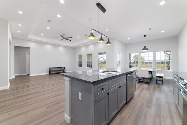 kitchen featuring dishwasher, gray cabinets, light hardwood / wood-style floors, decorative light fixtures, and a kitchen island