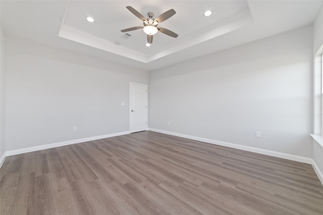 spare room with a tray ceiling, ceiling fan, crown molding, and wood-type flooring