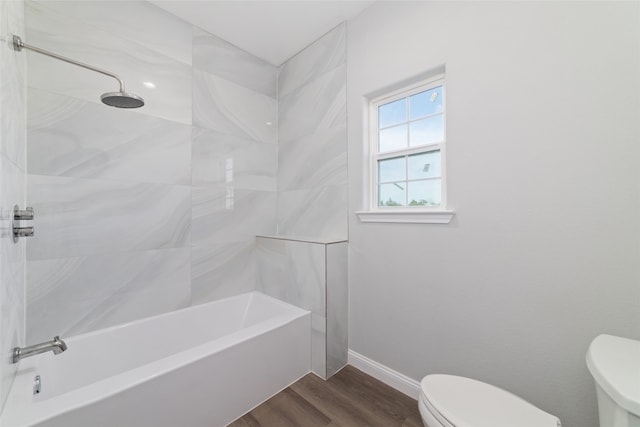 bathroom featuring wood-type flooring, tiled shower / bath combo, and toilet