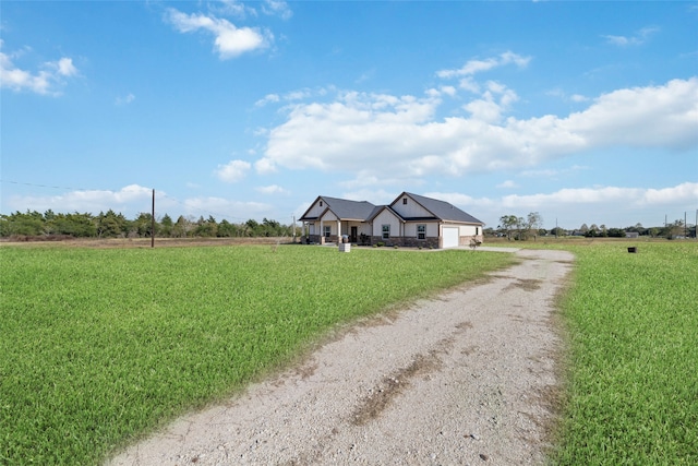 ranch-style home featuring a rural view, a front yard, and a garage