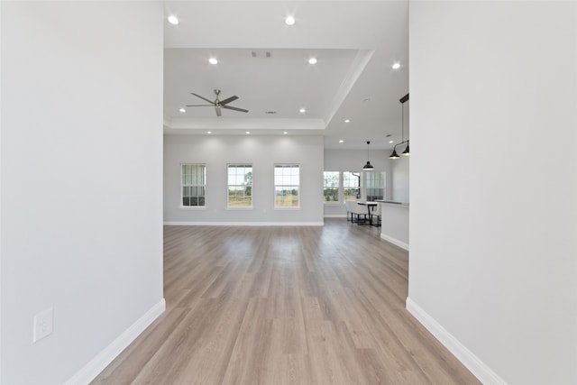 unfurnished living room featuring light hardwood / wood-style floors, a raised ceiling, and ceiling fan