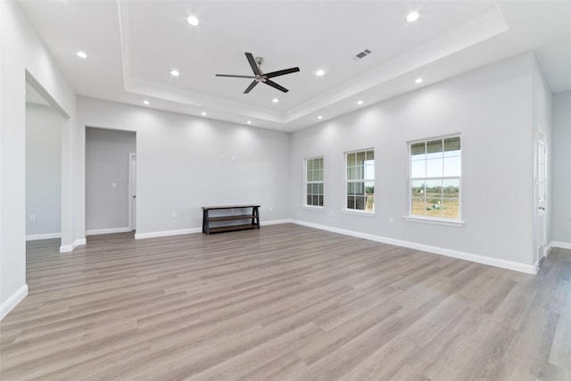 unfurnished living room with a tray ceiling, ceiling fan, and light hardwood / wood-style flooring