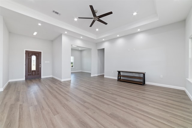 unfurnished living room featuring ceiling fan, light wood-type flooring, and a tray ceiling