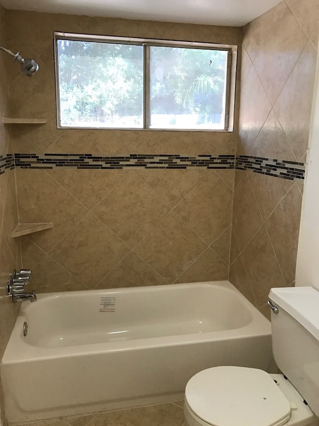 bathroom featuring toilet and tiled shower / bath