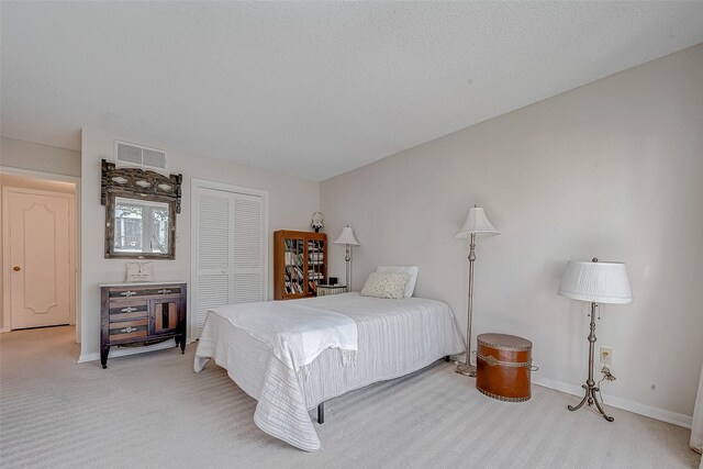 carpeted bedroom featuring a textured ceiling and a closet