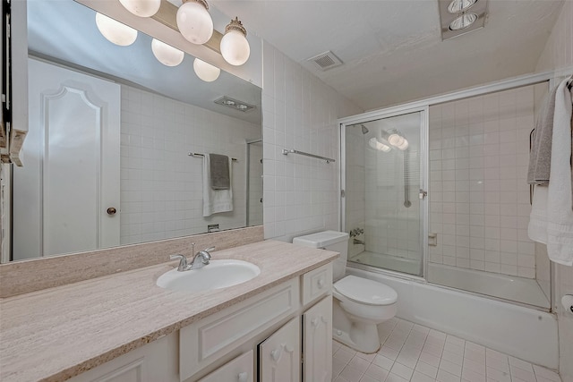 full bathroom with combined bath / shower with glass door, tile walls, vanity, toilet, and tile patterned floors