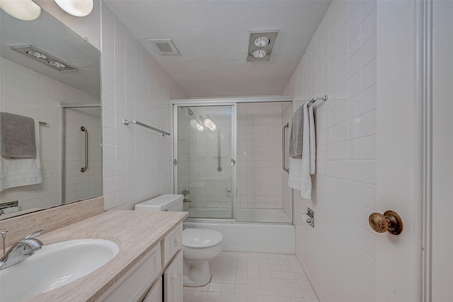 full bathroom with combined bath / shower with glass door, tile walls, vanity, tile patterned floors, and toilet