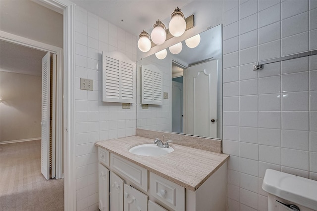 bathroom with vanity, toilet, and tile walls