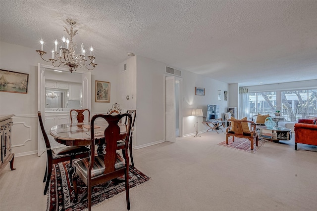 carpeted dining space with a notable chandelier and a textured ceiling