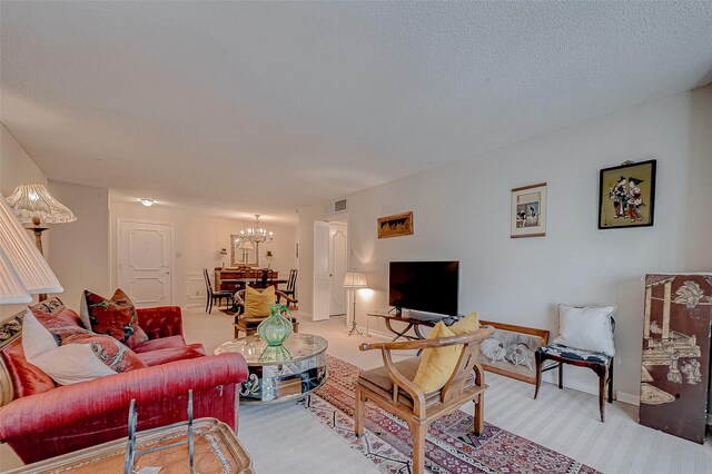 carpeted living room featuring a textured ceiling and a chandelier