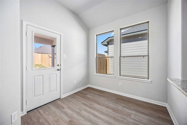 foyer entrance with light hardwood / wood-style floors and vaulted ceiling