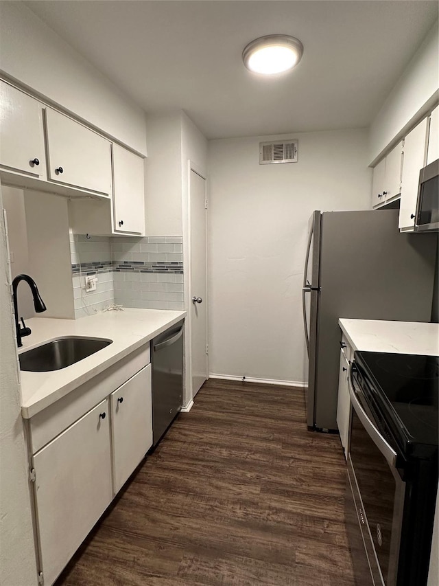 kitchen featuring backsplash, dark wood-type flooring, sink, white cabinetry, and stainless steel appliances