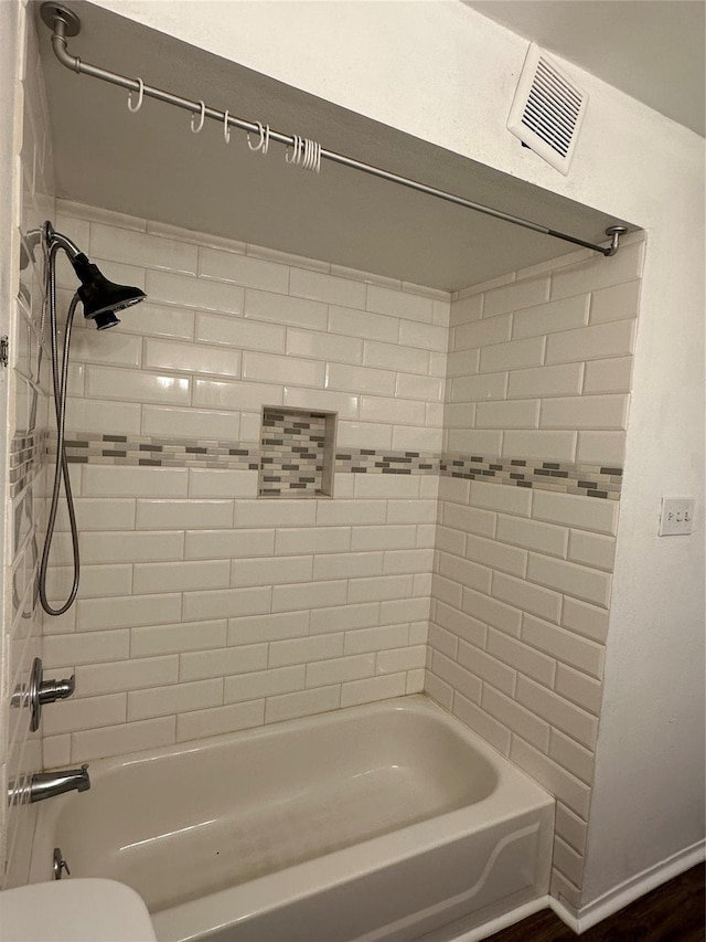 bathroom with toilet and tiled shower / bath