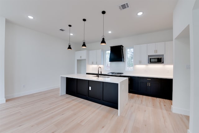 kitchen with premium range hood, sink, white cabinets, and appliances with stainless steel finishes