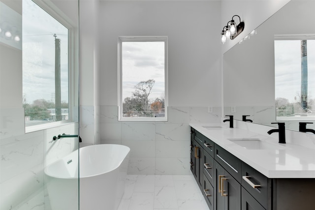 bathroom featuring a tub to relax in, vanity, and tile walls