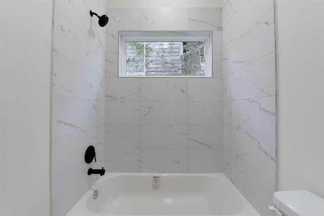 bathroom featuring tiled shower / bath combo and toilet