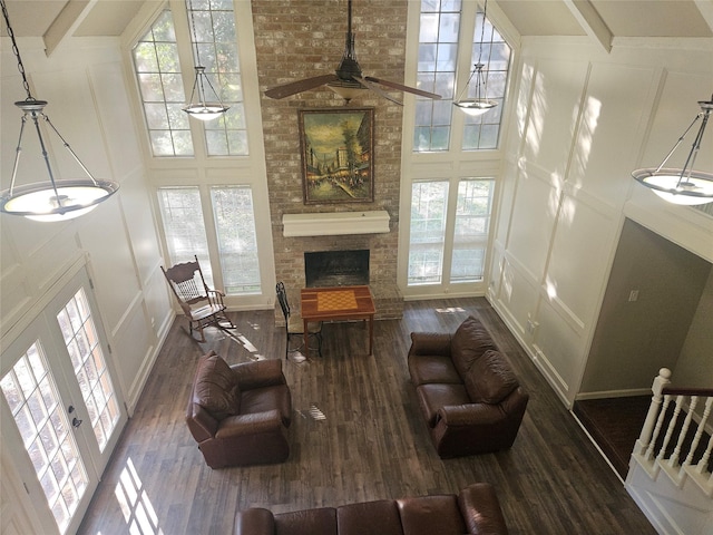 living room featuring beam ceiling, a towering ceiling, dark wood-type flooring, and french doors