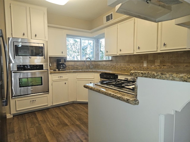 kitchen with stainless steel appliances, extractor fan, sink, dark stone countertops, and white cabinetry