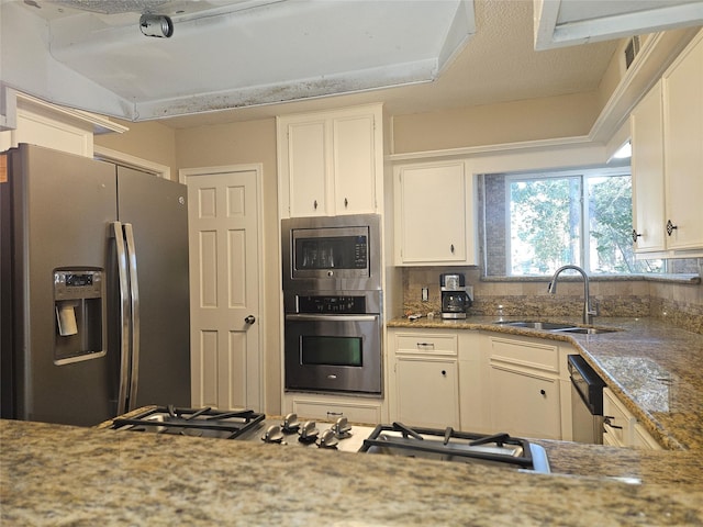 kitchen with light stone countertops, appliances with stainless steel finishes, white cabinetry, and sink