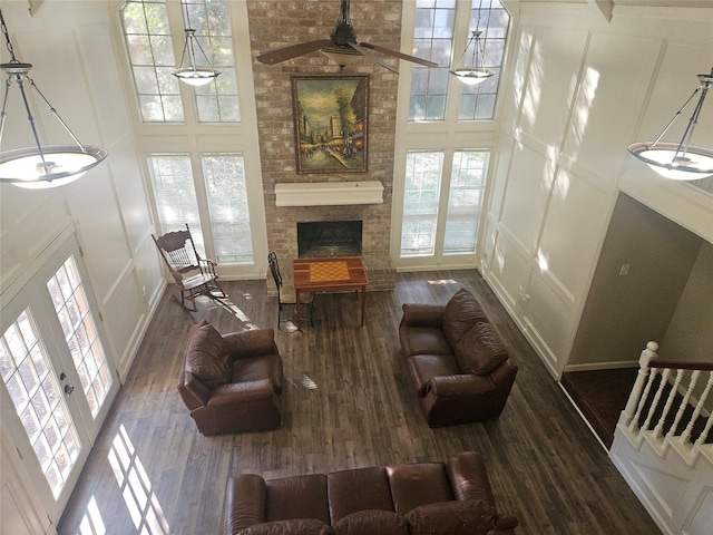 living room featuring dark hardwood / wood-style floors, a towering ceiling, a fireplace, and a wealth of natural light