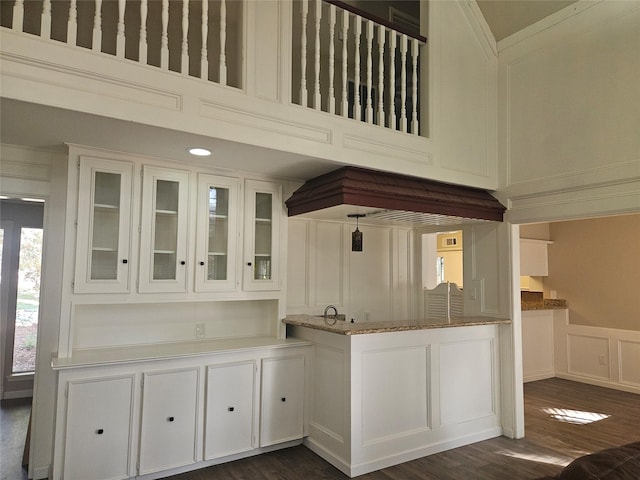 kitchen featuring white cabinets, dark hardwood / wood-style flooring, and light stone countertops