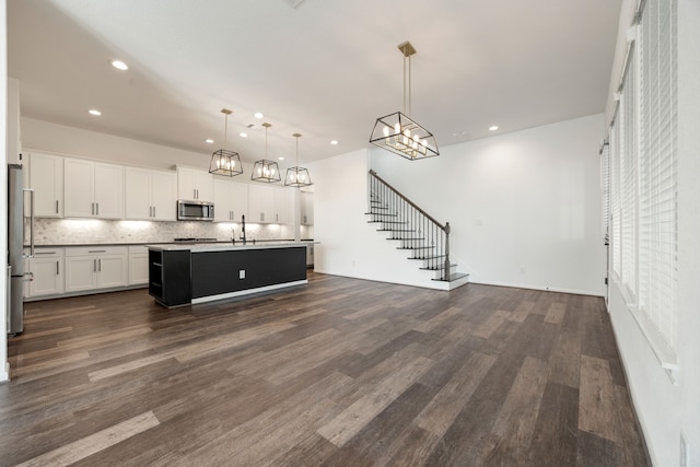 kitchen featuring stainless steel appliances, a kitchen island with sink, pendant lighting, white cabinets, and dark hardwood / wood-style floors