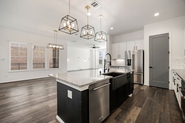 kitchen with ceiling fan, stainless steel appliances, dark hardwood / wood-style flooring, pendant lighting, and a center island with sink